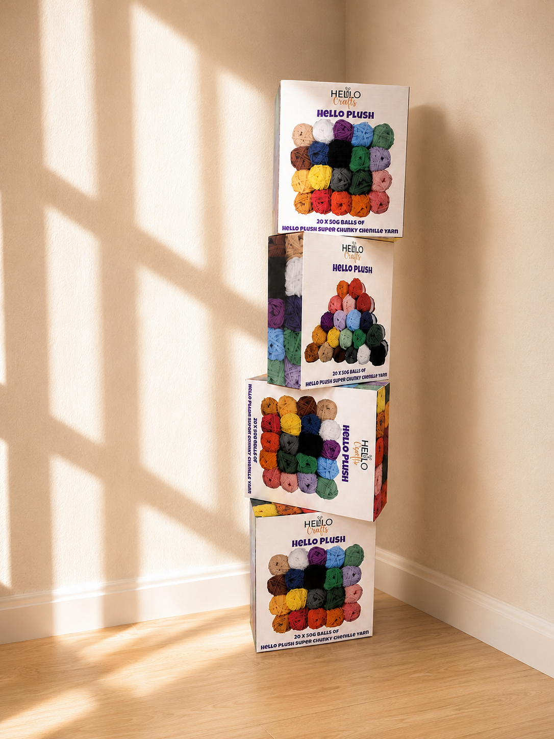 4 boxes of Hello Plush yarn stacked in a bright room on a wooden floor