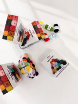 Hello Plush yarn boxes stacked in warm natural light showing the full colour range